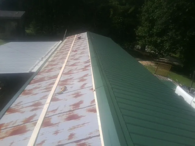 Old rusted panels beside newly installed green metal roofing — Wind Damage Roof Repair by Roofing Brothers in North Chatham