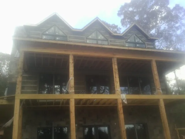 Dormers and porch framing on a large log home under construction — Roof Coating work by our crew in North Chatham
