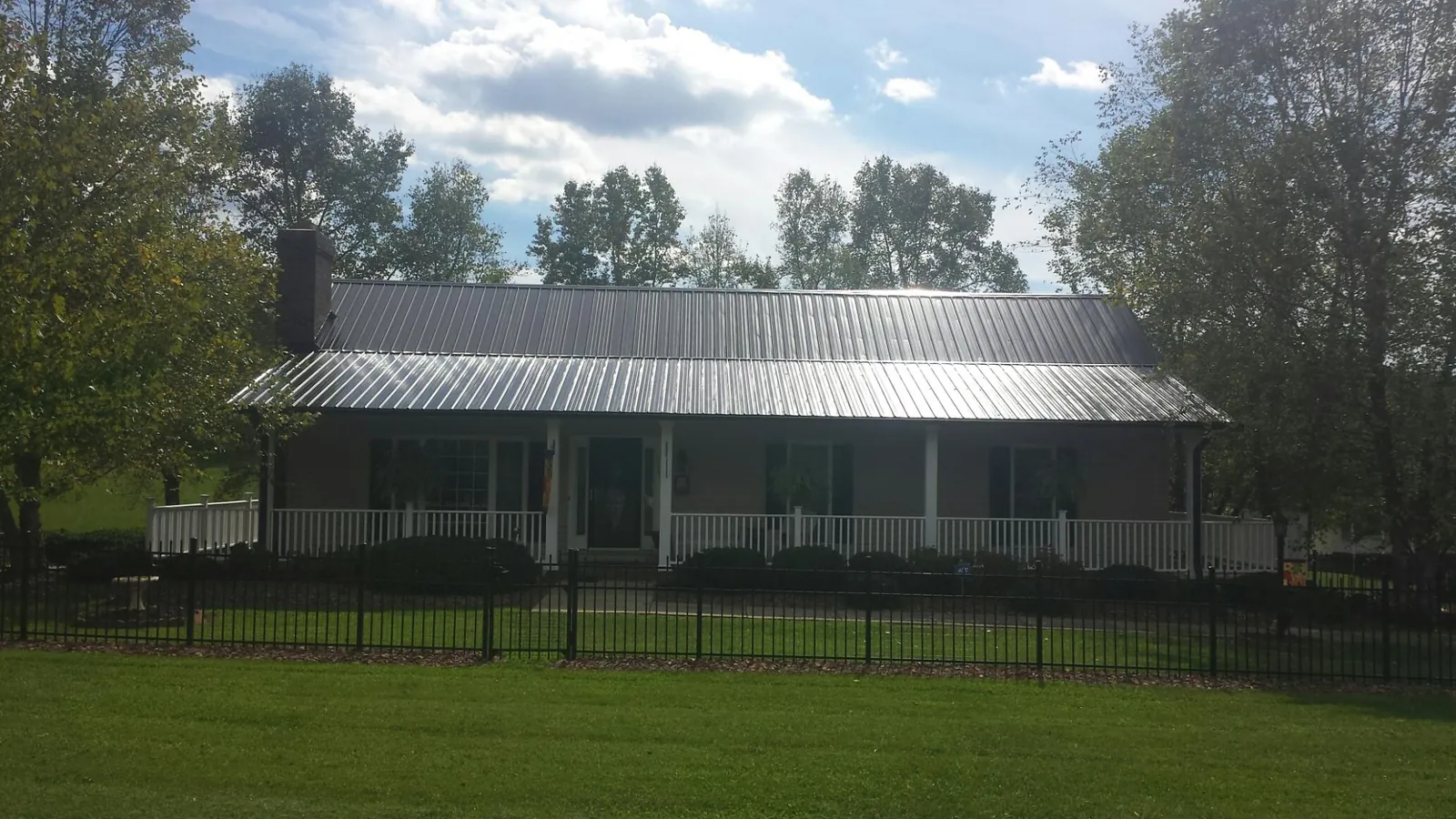 Gray metal roof on a brick ranch with a full width front porch — Gutter Guard Installation work by our crew in North Chatham