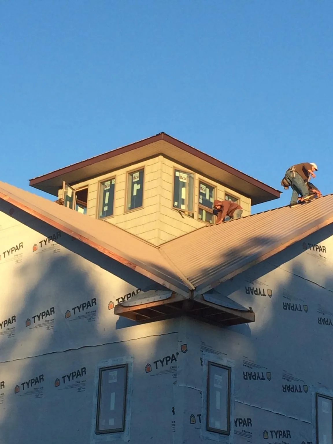 Roofers working around a rooftop cupola on a new metal roof at sunset — Roof Waterproofing in North Chatham by Roofing Brothers
